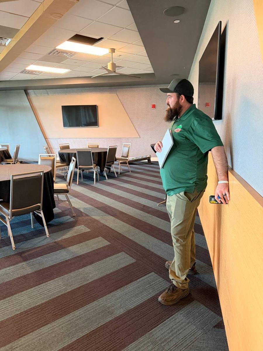 Shane from Gator Carpet and Tile measuring a room with a laser measure